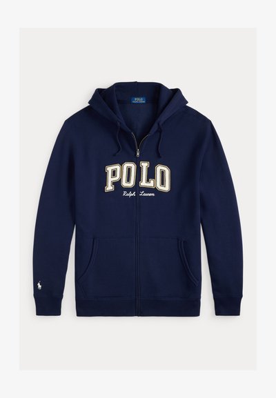 Námornícka mikina na zips vyrobená z bavlny s predným kloktacím vreckom. Obsahuje vyšitý nápis "POLO" v béžovej farbe a malú emblemu jazdca na rukáve.