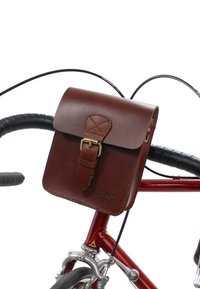Borsa per bicicletta in pelle marrone con pattina ripiegabile, fibbia in metallo e dettagli cuciti, montata sul manubrio di una bici.