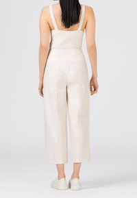 Ljust beige cropped byxor i mjuk kvalitet, tillsammans med en åtsittande ribbad linne. Outfiten har vida ben och en minimalistisk design.