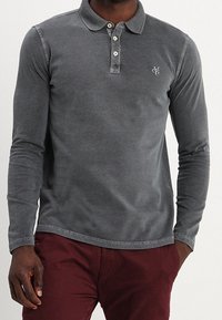 Long-sleeve, gray polo shirt made of soft cotton. Features a collared neckline, three-button placket, and a small embroidered logo on the chest.