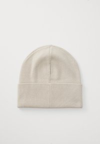 Beige knit beanie with a rolled brim. It features a smooth texture and a fitted, rounded shape. Simple and minimal design.