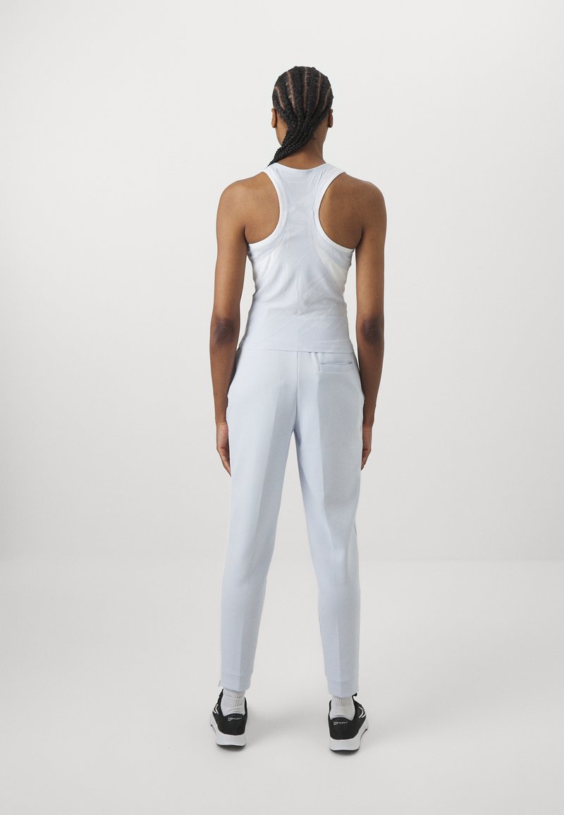 Weiße Tanktop und hellblaue Jogginghose, figurbetontes Design, weicher Stoff, mit Racerback-Stil und seitlichen Taschen an der Hose.