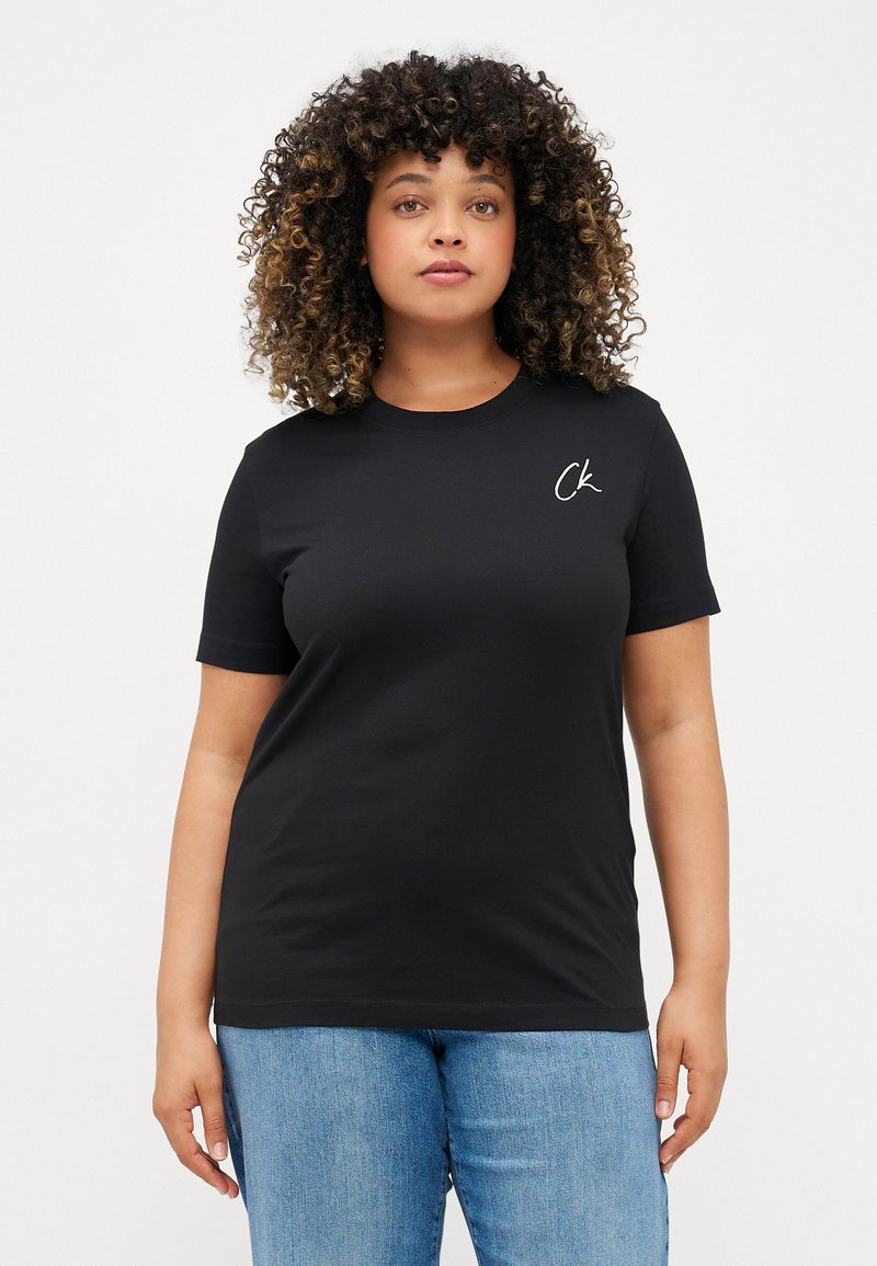 Μαύρο βαμβακερό μπλουζάκι με κοντό μανίκι, στρογγυλή λαιμόκοψη και μικρό λευκό λογότυπο 'ck' στην αριστερή πλευρά του στήθους. Φοριέται με ανοιχτό μπλε τζιν.