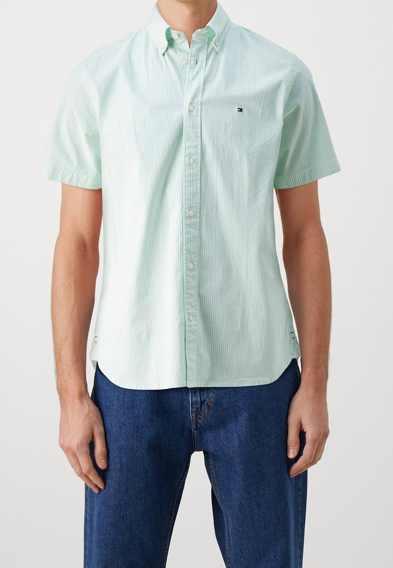 Camisa de botones de manga corta en verde claro con franjas blancas delgadas alternas. Presenta un cuello y un pequeño logo en el pecho.
