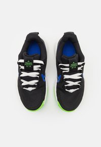 Black athletic shoes with white laces, blue accents, and green soles; textured upper and padded collar for comfort.
