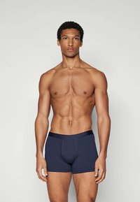 Dunkelblaue Boxershorts mit glatter Textur und elastischem Bund, die einen engen Sitz und ein verstärktes Frontfach-Design aufweisen.