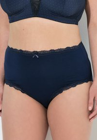 Mutande navy a vita alta con pizzo lungo la cintura e le aperture delle gambe, dotate di un piccolo fiocco in satin al centro davanti.