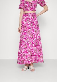 Ensemble deux pièces composé d'un top court avec des manches bouffantes et d'une longue jupe maxi. Les deux pièces présentent un motif floral rose sur un fond clair.
