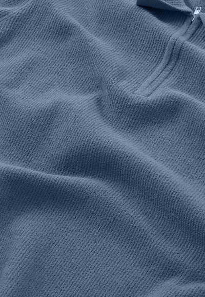Fleece-Pullover in Dunkelblau mit strukturierter Oberfläche, ausgestattet mit einem halben Reißverschlusskragen und dezenten Nähten. Weicher und leichter Stoff.