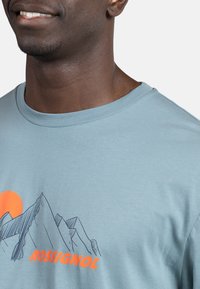 Lyseblå bomulds T-shirt med grafisk motiv af et bjerg og en orange sol. Rund halsudskæring, korte ærmer og glat tekstur.