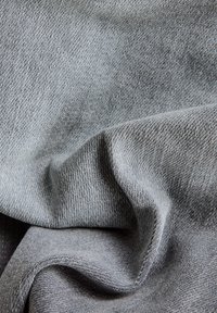 Tejido de punto gris con un tejido texturizado, que muestra suaves pliegues y tonos variados, enfatizando la elasticidad y flexibilidad del material.