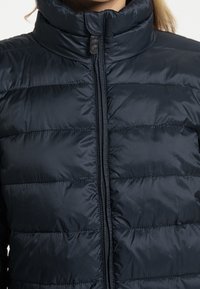 Granatowa kurtka puchowa z wysokim kołnierzem i zamkiem z przodu, z pikowanym wzorem i gładką, błyszczącą fakturą.