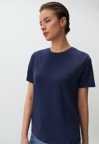 Marineblauw T-shirt met korte mouwen, gemaakt van gladde katoenen stof, voorzien van een ronde halslijn en een relaxte pasvorm. Eenvoudig ontwerp zonder patronen.