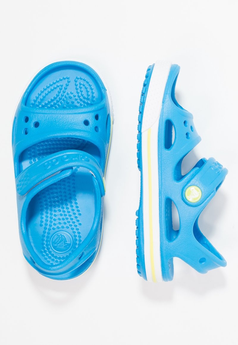 Sinilä plastik sandaalid reguleeritava rihmaga, ventilatsiooniks perforatsioonidega, tekstuuriga sisetald ning valge tallaga, millel on kollane aktsentlint.