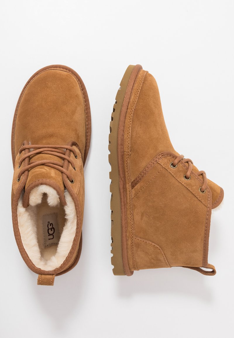 Brown suede ankle boots with a textured finish, reinforced stitching, and a fur-lined interior. Features round laces and a rubber sole.