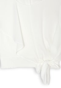 Blusa bianca leggera con design drappeggiato, scollatura arrotondata e dettaglio con fiocco in vita. Tessuto morbido con finitura liscia.