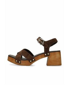 Sandale en daim marron avec talon bloc en bois, brides croisées, clous argentés et boucle réglable à la cheville.
