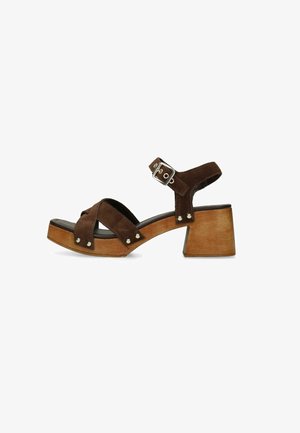 Sandale en daim marron avec talon bloc en bois, brides croisées, clous argentés et boucle réglable à la cheville.