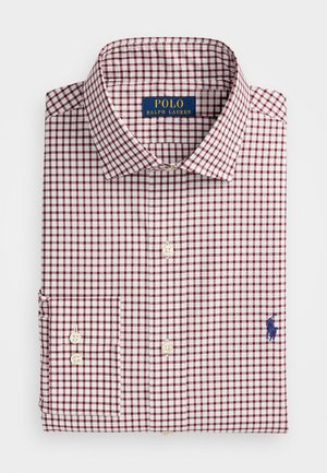 Chemise à carreaux rouge et blanc avec col ouvert, présente un logo bleu brodé sur la poitrine et un détail de poignet à deux boutons.