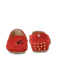 Des mocassins en daim rouge présentent un détail de gland sur le dessus, avec une semelle plate ornée de picots en caoutchouc ronds pour l'adhérence. Doublure intérieure lisse.