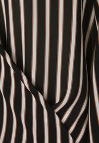 Černá látka s vertikálními pruhy v bílé a rezavé barvě. Hladký povrch s pruhy různé šířky, což vytváří vrstvený vzhled.