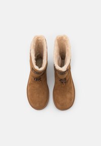 Paire de bottes d'hiver en daim couleur sable avec doublure intérieure moelleuse de couleur crème et fermetures réglables par cordon, vue de dessus sur fond blanc.