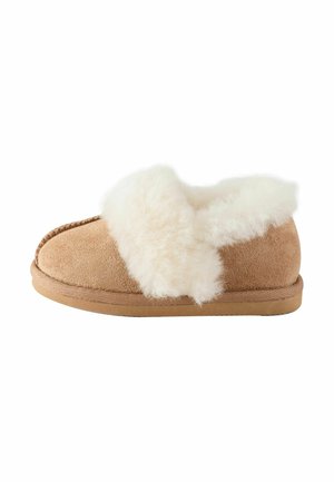 Beige Wildleder-Slipper mit dicker, weißer, flauschiger Innenfütterung und Kragen, flache Gummisohle, Seitenansicht.