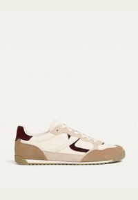 Baskets beiges et crème en matériaux daim et cuir, avec des accents bordeaux, une semelle texturée et un design athlétique classique.