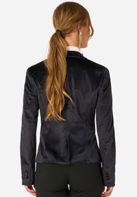 Mörkblå sammetsskjorta med skräddarsydd passform, enkelknäppt stängning och knappar som detaljer på ärmarna. Mjuk textur, strukturerade axlar.