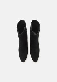 Bottines en daim noir avec un bout pointu, des fermetures éclair latérales et une texture lisse. Conçues pour une silhouette élégante et ajustée.