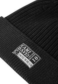 Black knit beanie with ribbed texture, featuring a rectangular tag that reads "CAM DAVID" and "LIMITED TM NO. 01/09."