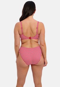 Rood-witte bikini-set met patroon, bestaande uit een ondersteunend zwemtopje en hoge taille broekje, gemaakt van rekbaar materiaal met brede bandjes.