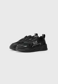 Zwarte sportsneakers van mesh en synthetisch materiaal, met een dikke zool, reflecterende accenten en een logo aan de zijkant.