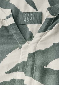 Kevyt V-kaula-aukko blouse vihreällä ja beigellä abstraktilla kuviolla. Kangas näyttää pehmeältä ja sileältä; tarrassa lukee "CRESCENDO."