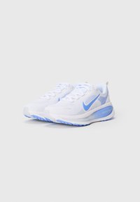 Valged spordijalatsid helesiniste aktsentidega, võrksus, tekstuuriga disain ja kummist talla. Küljel on silmapaistev Nike'i logo.