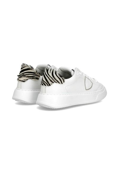Hvide sneakers lavet af glat læder med et tekstureret zebra-stribet faux pels-tilbehør på hælen. Gummisål med en let platform.