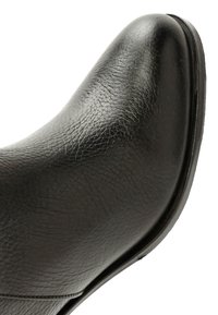 Czarna skórzana boot z gładką fakturą, zaokrąglonym czubkiem i niskim obcasem. Posiada minimalne przeszycia i prostą, zakrzywioną formę.