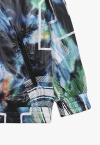 Letvægtsjakke i blå, gr�øn og sort tie-dye mønster. Har en lynlåslomme, elastiske ærmer og grafiske hvide detaljer. Tekstureret stof.