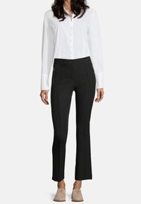 Weißes Hemd mit Kragen, kombiniert mit schwarzen, taillierten Hosen mit Reißverschlusstaschen vorne und einer eleganten Silhouette.