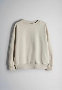 Sudadera beige clara con cuello redondo, mangas largas, puños acanalados y dobladillo, mostrada sobre un fondo gris claro y liso.
