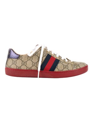 Zapatilla baja con estampado beige del monograma GG, raya lateral roja y azul, suela roja, cordones blancos y lengüeta trasera metálica morada.