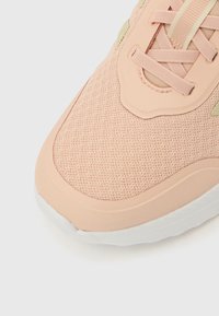 Pantof sport roz deschis, cu partea superioară din plasă, guler căptușit și talpă moale. Accentele includ un finisaj texturat și șireturi contrastante.