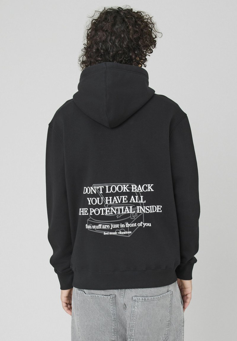 Hoodie noir en mélange de coton, avec un grand motif de texte blanc au dos comprenant des citations motivantes et une texture douce et lisse.