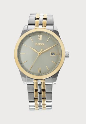 Silver and gold wristwatch with round face, gold hour markers, date display at 3 o'clock, and matching metal link bracelet.