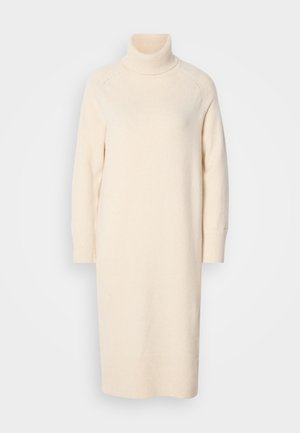 Robe pull col montant de couleur crème fabriquée à partir d'un tissu doux. Présente des manches longues et une coupe décontractée, avec des détails côtelés au niveau du col et des poignets.