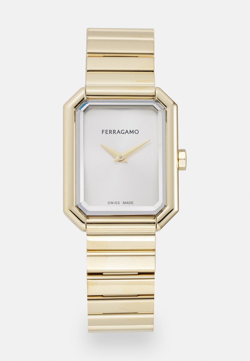 Złoty zegarek ze stali nierdzewnej o ośmiokątnym deklu, białej tarczy i złotych wskazówkach. Posiada bransoletę o połączonym designie z polerowanym wykończeniem.