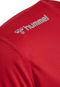 Rode sportieve jersey van een gestructureerde stof, met korte mouwen en een zilveren "hummel" logo op de bovenste linker schouder.