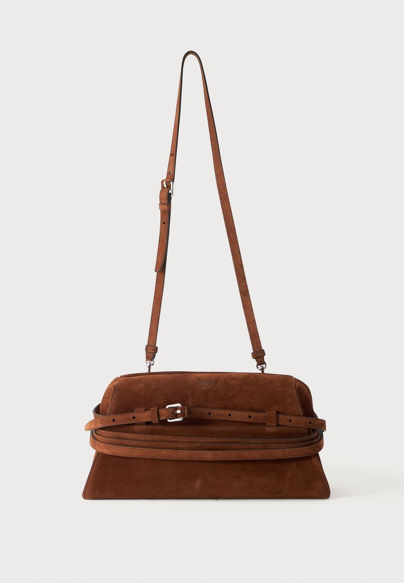 Sac à épaule en daim marron avec une longue bandoulière ajustable et un détail de boucle sur le devant, présenté sur un fond uni.