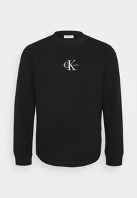 Zwarte sweatshirt met lange mouwen en ronde hals, wafelstructuur en wit Calvin Klein Jeans-logo en opschrift op de borst.