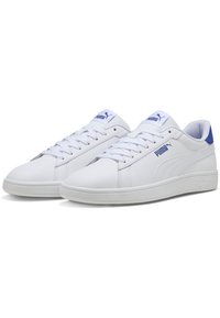 Sneaker bianche con finitura in pelle liscia, dettagli blu sul tallone e sulla linguetta, design con lacci e suola in gomma testurizzata.